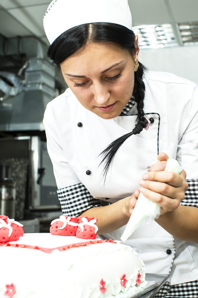 Pastry chef decorates a cake - Foto, afbeelding