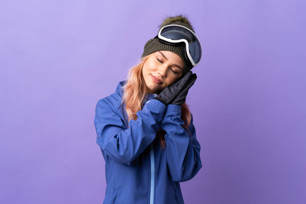 Menina adolescente esquiador com óculos de snowboard sobre fundo roxo isolado fazendo gesto de sono em expressão adorável
 - Foto, Imagem