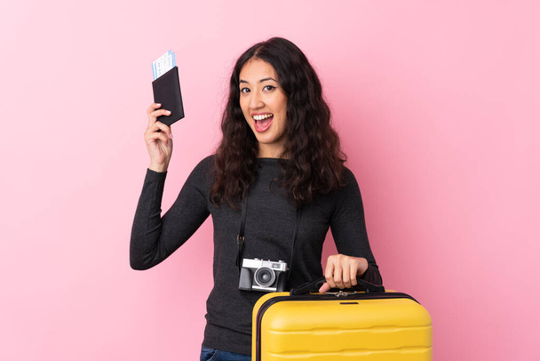 Mixed rodun nainen yli eristetty vaaleanpunainen tausta lomalla matkalaukku ja passi - Valokuva, kuva