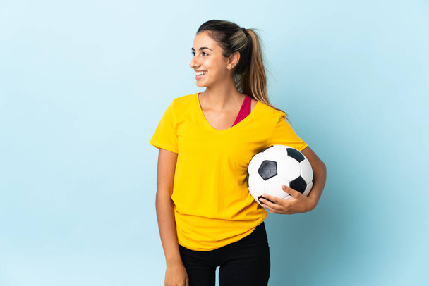 Молода жінка іспаномовного футболіста над ізольованою на синьому фоні, дивлячись на сторону
 - Фото, зображення