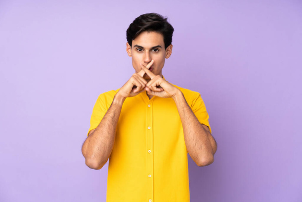 Человек на изолированном фиолетовом фоне показывает знак молчания жеста - Фото, изображение