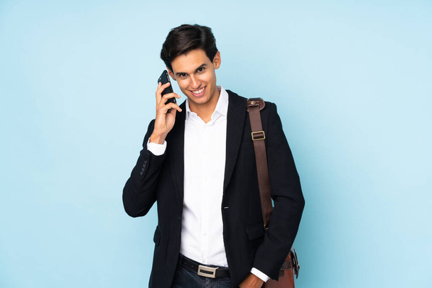 Бізнесмен над ізольованим синім фоном робить жест телефону
 - Фото, зображення
