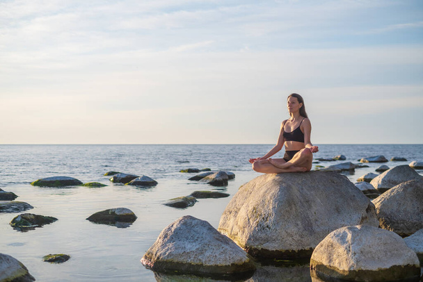 Młoda kobieta medytująca w pobliżu morza - Zdjęcie, obraz