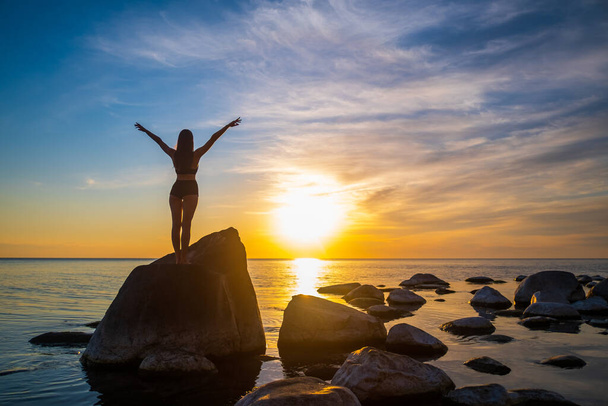 Nierozpoznana kobieta ciesząca się wolnością podczas zachodu słońca - Zdjęcie, obraz
