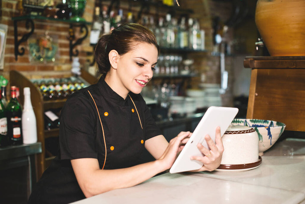Waitress in bar with tablet looking orders - Foto, Imagen