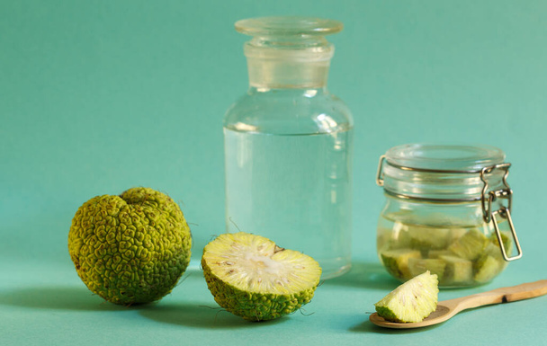 Green fruit osage orange, jar with tincture on a green background, horizontally with space - Photo, Image