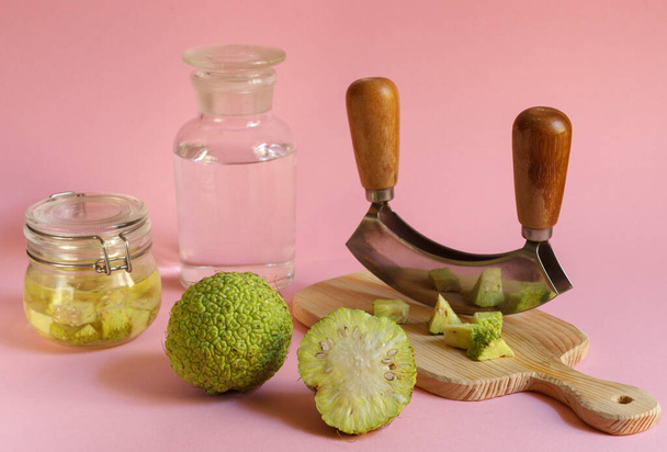 Osage zielone jabłko i tablicę z plasterkami owoców do produkcji nalewek leczniczych. Poziomy na różowym tle - Zdjęcie, obraz