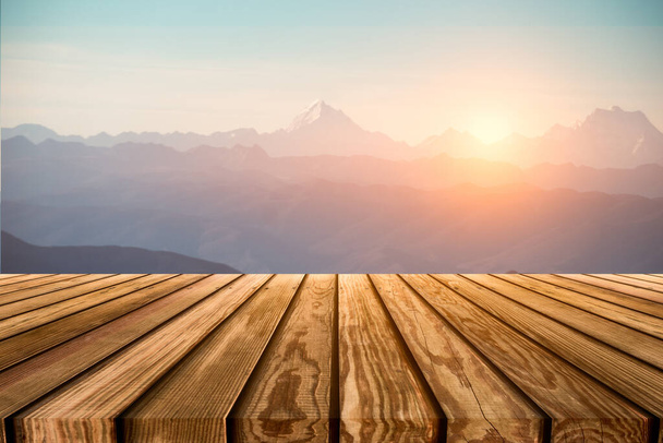 Brown wooden table top on blurred peak on mountain range with sunrise at morning  - Photo, Image