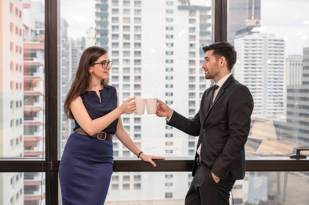 Young caucasian business colleague holding and cheers coffee cup in modern office at business district - Photo, Image