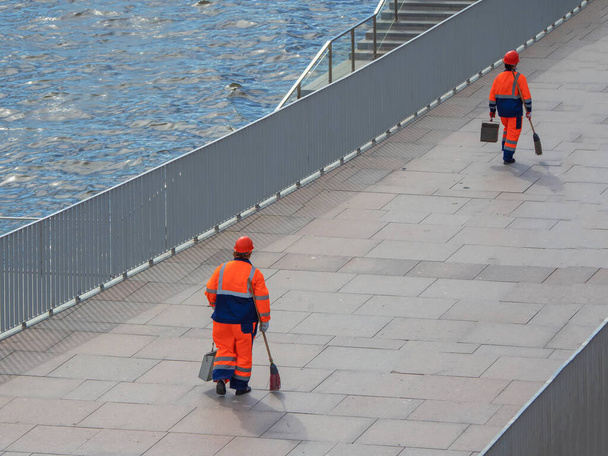 Városi munkások a városi utcában, takarítók seprűvel és szemetessel a kezükben. Városi takarítás - Fotó, kép