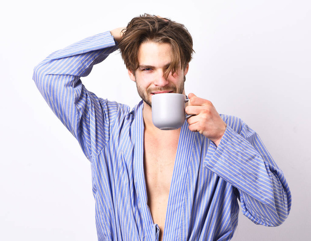 Sexy fit macho with flirty face in bathrobe holds mug. - Foto, afbeelding