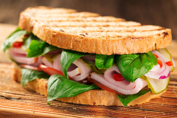 Плакат вкусный сэндвич с ветчиной крупным планом на деревянной кухне, вид сверху - Фото, изображение