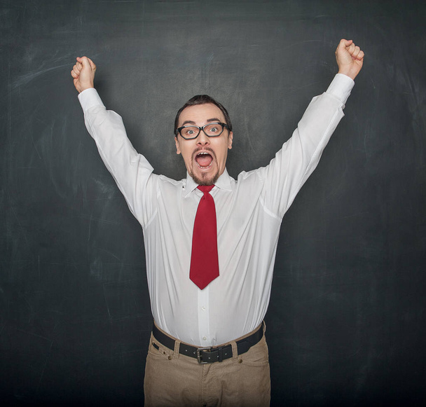 Successful handsome happy man with raising arms on chalkboard background - Photo, Image