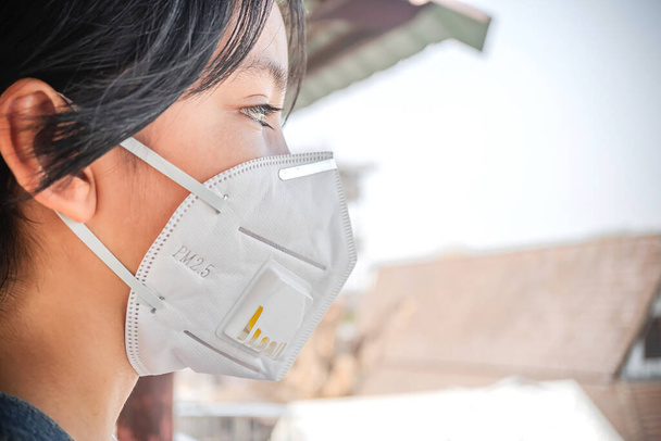Concetto Coronavirus e inquinamento atmosferico pm2.5. Giovane ragazza che indossa maschera protettiva per la diffusione della malattia di Coronavirus 2019. Primo piano di giovane ragazza con maschera N95 sul viso - Foto, immagini