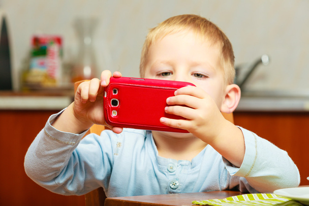 Happy childhood. Blond boy kid child playing with mobile phone - 写真・画像