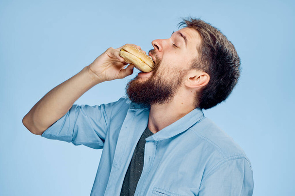 Un hombre con una hamburguesa en las manos un bocadillo comida rápida camisa azul con una corbata - Foto, imagen