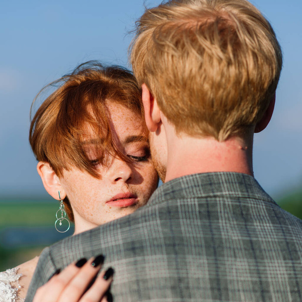Very nice redhead young just married happy couple kissing in the sunset outdoors - Foto, immagini