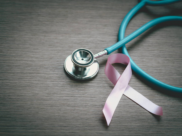 Sensibilizzazione al cancro al seno nastro rosa con stetoscopio medico su fondo di legno, simbolo ottobre, concetto di sanità e medicina - Foto, immagini