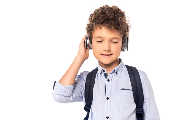 schoolboy with closed eyes touching wireless headphones isolated on white  - Fotó, kép