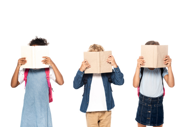 multicultural schoolgirls and schoolboy covering faces with books isolated on white  - Photo, Image