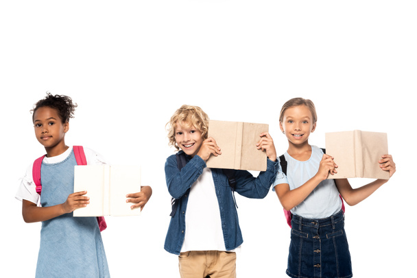 multicultural schoolgirls and curly schoolboy holding books isolated on white  - Φωτογραφία, εικόνα