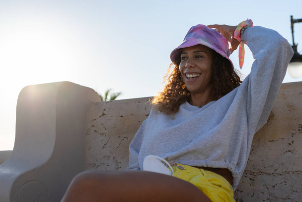 Retrato de una atractiva joven negra sentada relajada al aire libre sin máscara. Concepto nueva forma de turismo - Foto, Imagen