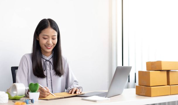 Азійська бізнесменка бере онлайн-замовлення від ноутбука і розмовляє з клієнтами, щоб підтвердити їх замовлення, продавати продукти онлайн або робити вільну роботу вдома концепція. - Фото, зображення
