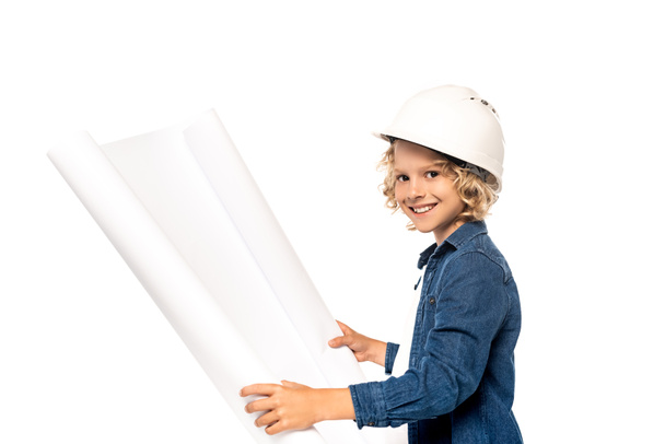 blonde boy in safety helmet and costume of architect holding blueprint and looking at camera isolated on white - Foto, Bild