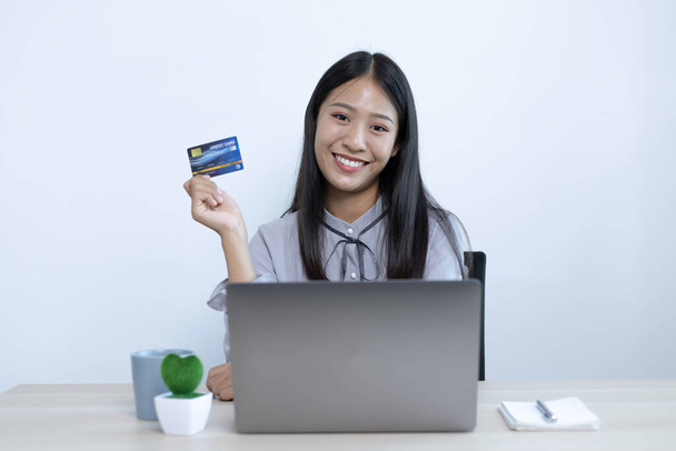 Nuoret naiset tekevät mielellään ostoksia verkossa ja pitävät luottokortteja maksujen suorittamiseksi Internetissä kannettavassa tietokoneessa, verkkokaupoissa ja luottokorttimaksussa. - Valokuva, kuva