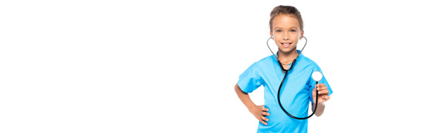website header of kid in costume of doctor holding stethoscope while standing with hand on hip isolated on white  - Photo, Image