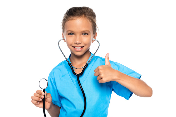 child in costume of doctor holding stethoscope while showing thumb up isolated on white  - Фото, зображення