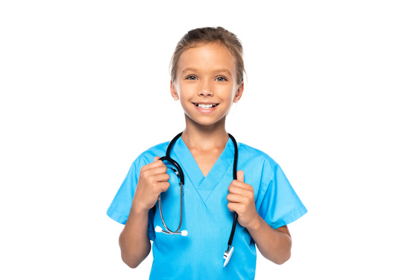 child in costume of doctor touching stethoscope and looking at camera isolated on white  - Zdjęcie, obraz