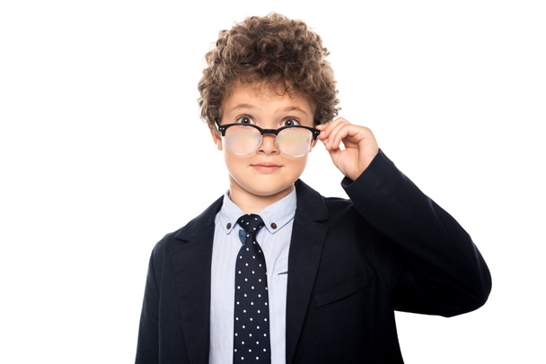 curly boy in suit touching glasses and looking at camera isolated on white - Fotoğraf, Görsel