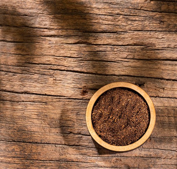 Black tea powder in wooden bowl - Camellia sinensis - Photo, image