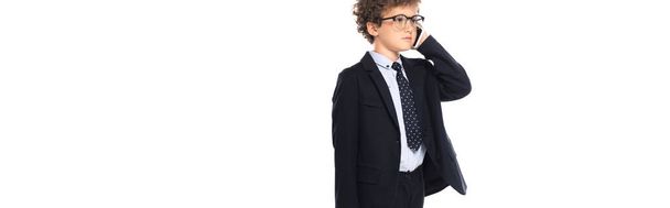 panoramic crop of curly boy in suit and glasses talking on smartphone isolated on white - Fotó, kép