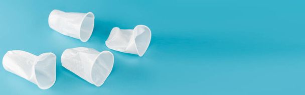 disposable plastic crumpled cups on blue background, panoramic shot - Фото, изображение