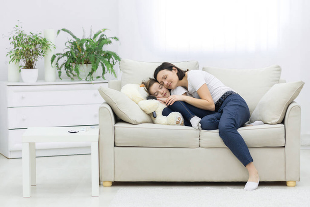 Smiling mother and daughter laying together in the living room. - Foto, Imagen