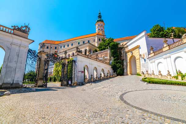 The Mikulov castle, Czech republic. Famous medieval castle on top of hill. Beautiful ornament garden with flowers, trees and green grass. Summer weather and blue sky. Beautiful wine region near Palava - 写真・画像