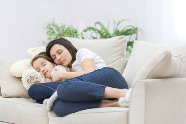 Photo of mom and daughter hugging and sleeping on sofa. - Photo, image
