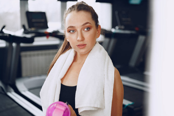 Young sporty woman having a drink in a gym after workout - Fotó, kép