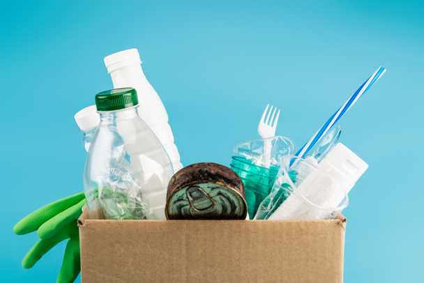 Plastikmüll und Gummihandschuhe in Karton isoliert auf blau - Foto, Bild