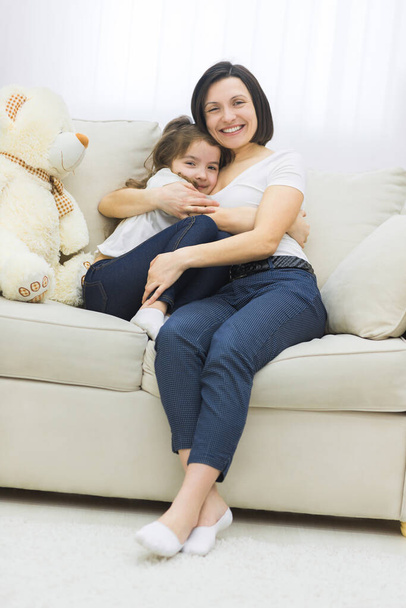 Photo of mother and daughter on white sofa. - Fotoğraf, Görsel