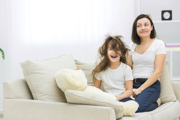 Photo of little girl with messy hair and her mother beside. - Foto, imagen
