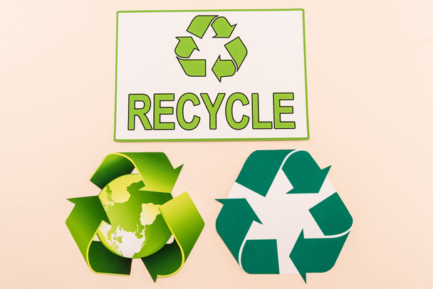 vista superior de símbolos de reciclagem verde com planeta e reciclar palavra isolada em bege - Foto, Imagem