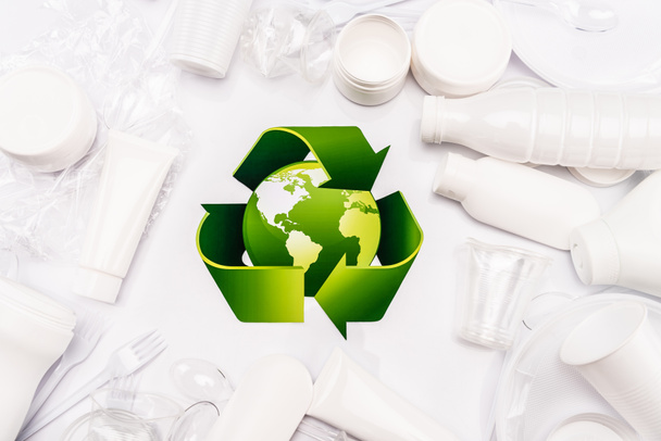 vista superior del cartel de reciclaje y basura plástica dispersa sobre fondo blanco - Foto, Imagen