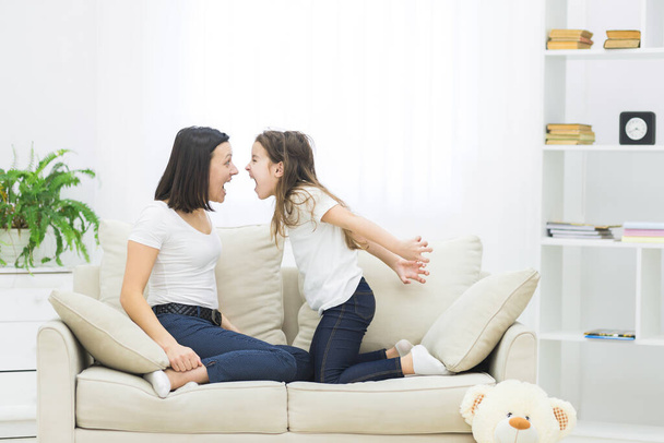 Photo of mother and daughter sitting playing on sofa. - Фото, зображення