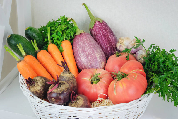 Herbstgemüse im Korb auf einem Regal im Holzregal neben einer weißen Wand. Vegetarische Kost: Gurken, Tomaten, Zucchini, Petersilie und Kürbis. - Foto, Bild