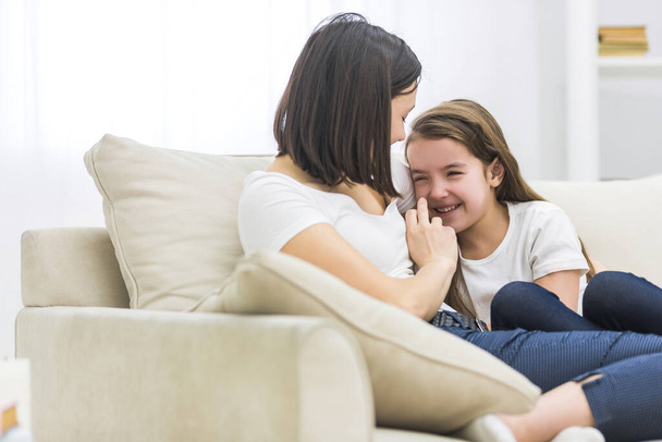 Photo of happy mother and daughter talking on sofa in living room. - Zdjęcie, obraz