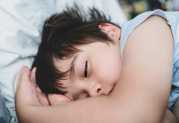 Cropped shot Child boy sleep with his eyes half open on his bed, Close up Young Kid sleeping with open eyed while taking a nap, Sleep problems in young children concept or REM sleep - Photo, image