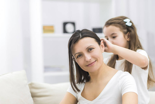 Photo of a daughter braiding her mothers hair in the morning after sleeping in bed. - Photo, image